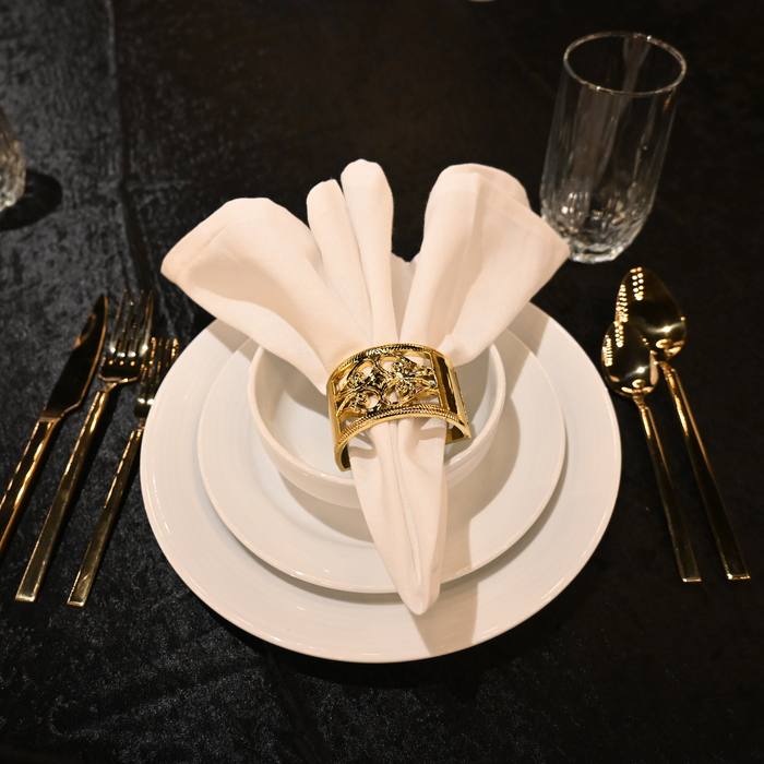 Place setting detail with gold napkin ring on black linen
