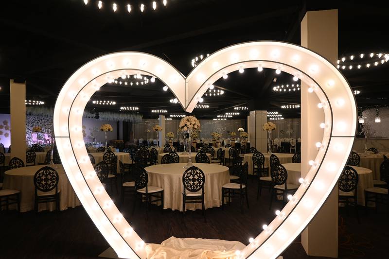 Reception venue styled with lit heart feature and banquet tables